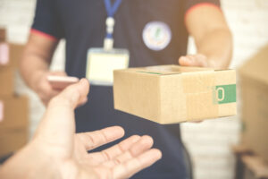 Delivery Man Smiling And Holding Cardboard Box E1618967895869